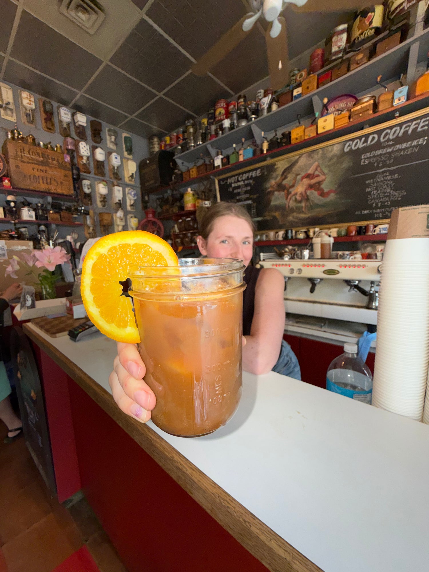Person holding a glass of iced tea with an orange slice in a coffee shop. iced-coffee-calgary-elektrospresso-summer-drink